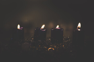 four black burning candles on advent wreath, dramatic and contract
