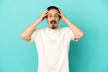 Young caucasian man isolated on blue background with surprise expression