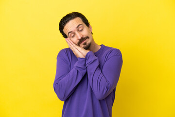 Fototapeta premium Young caucasian man isolated on yellow background making sleep gesture in dorable expression