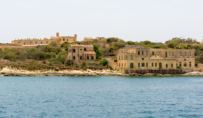 Fototapeta premium Old ruined buildings at Manoel Island in Gzira, Malta, with fort Manoel walls in the background.