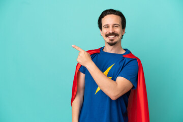 Super Hero caucasian man isolated on blue background pointing to the side to present a product © luismolinero