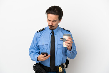 Young police man over isolated background white holding coffee to take away and a mobile
