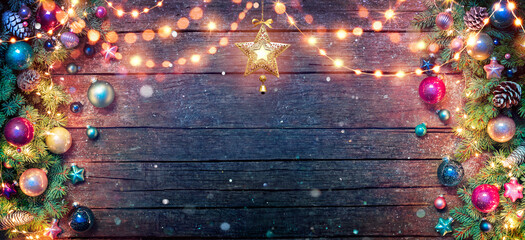 Christmas Decoration - Fir Branches And Baubles Illuminated With String Lights On Dark Wooden Table...
