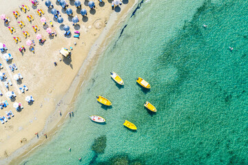 Aerial drone view of boats and beach with straw umbrellas with turquoise water. Ionian sea, Kefalonia Island, Greece.