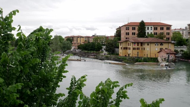 Kayak training in the dora river in Ivrea. Frame of trees. Panning. Real time 4K