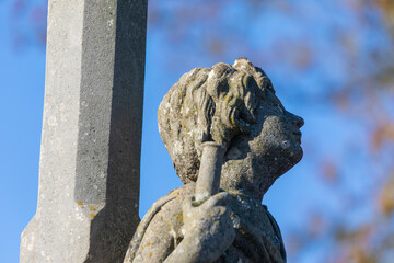 Stone sculpture or monument to an angel with an antimony sitting on a grave