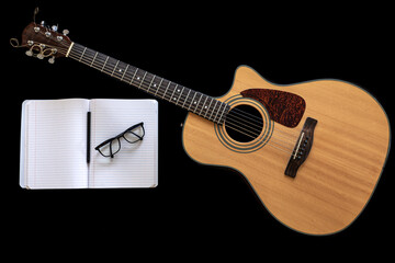 Classical acoustic guitar and an open notebook on a black background.
