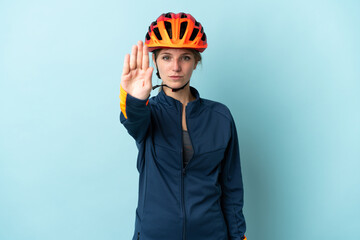 Young cyclist woman isolated on blue background making stop gesture