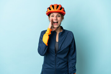 Young cyclist woman isolated on blue background with surprise and shocked facial expression - obrazy, fototapety, plakaty