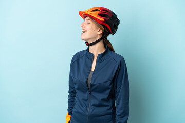 Young cyclist woman isolated on blue background laughing in lateral position - obrazy, fototapety, plakaty