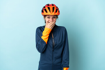 Young cyclist woman isolated on blue background happy and smiling covering mouth with hand - obrazy, fototapety, plakaty