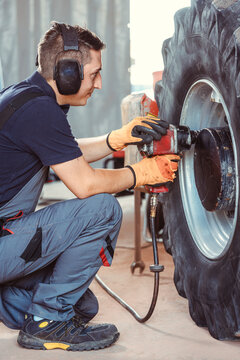 Farm Machine Mechanic Working On Wheel With Power Tool