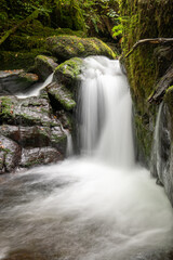 Long exposure of a waterfall on the Hoar Oak Water river flowing through the woods at Watersmeet in Exmoor National Park