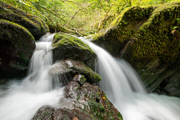 Long exposure of a waterfall on the Hoar Oak Water river flowing through the woods at Watersmeet in Exmoor National Park