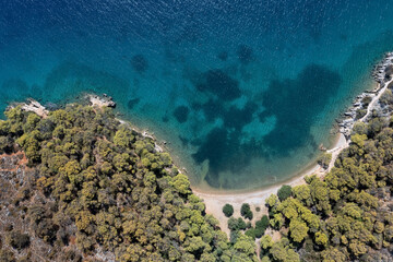 Aerial view of an empty tiny white sand beach surrounded by trees and rocks, Peloponnese, Greece