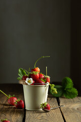 juicy red strawberries in a mini bucket on a wooden background. High quality photo