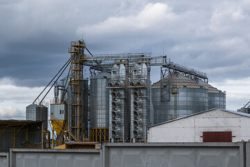 Fototapeta na wymiar modern granary elevator and seed cleaning line in silver silos on agro-processing and manufacturing plant for storage and processing drying cleaning of agricultural products, flour, cereals and grain