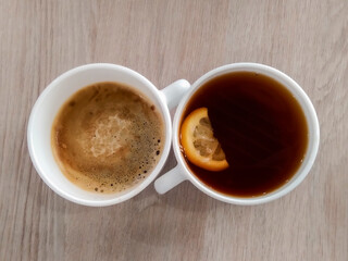 a cup of black coffee and a cup of tea with a lemon slice, top view, wooden background
