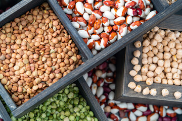 Different types of cereals: beans, chickpeas and lentils in wooden compartment box, healthy food, wallpaper and texture.
