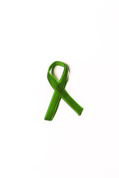 Green velvet ribbon on white background. World Mental Health Day. Cancer Awareness Symbolic Ribbon.