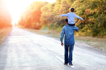 A Happy parent with a child in the park hands on nature travel go along the road