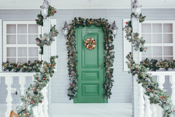 Green door entrance to the house. Christmas festive deco decorated with Christmas tree branches