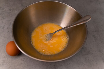 Chicken eggs, beaten with a fork in a metal omelet bowl