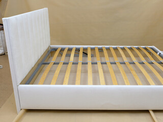 Fototapeta na wymiar Production. Bed upholstered in white fabric without mattress. Wooden slats.