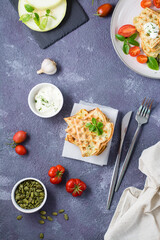 A stack of ready-to-eat zucchini waffles and basil on baking paper on the table. Vegetable dietary vegetarian food. Top and vertical view