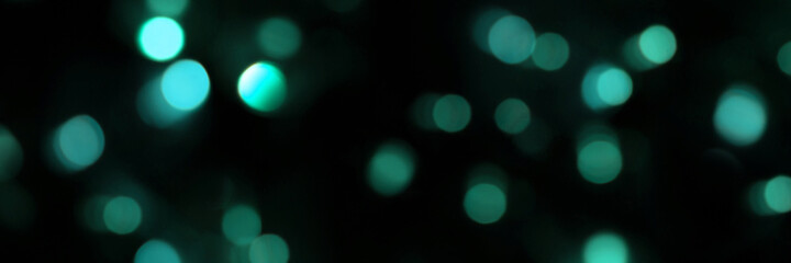 Banner of defocused bokeh lights on black background, an abstract naturally blurred backdrop for Christmas eve or birthday party. Festive light texture. Blue garland in blur. Overlay effect for design