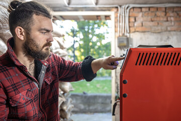 The man with solid fuel boiler, working with biofuels, economical heating.
