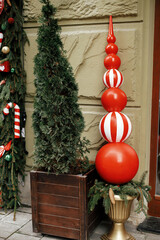Stylish christmas candy cane, spruce branches, red decoration on window or door of building or shop. Christmas festive  decor for winter holidays in european city street. Merry Christmas!