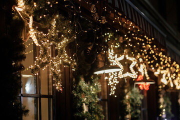 Stylish christmas star illumination and spruce branches in golden lights in evening, fairytale decoration. Atmospheric magic time. Christmas festive decor for winter holidays in city street