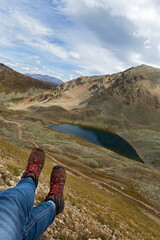 Feet of a tourist  on a high hill above a mountain lake