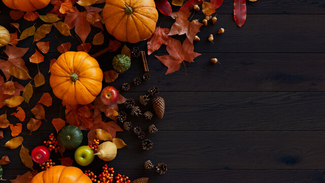 Thanksgiving Wallpaper with Fall leaves, Gourds and Acorns on a Dark wood Tabletop.
