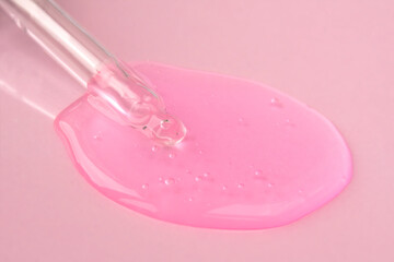Pipette with fluid hyaluronic acid on pink background. Cosmetics and healthcare concept closeup. Dose of serum or retinol with air bubbles. Flat lay. Luxury gel or beauty product presentation in macro