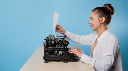 happy young woman is an author at a typewriter, is inspired,