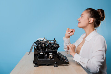 young woman writer at a typewriter, is inspired, is passionate about writing a text.