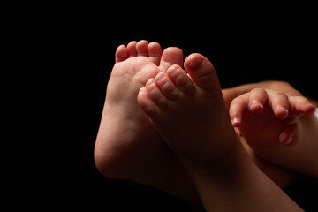 Close up newborn fingers feet and hands isolated on black background 