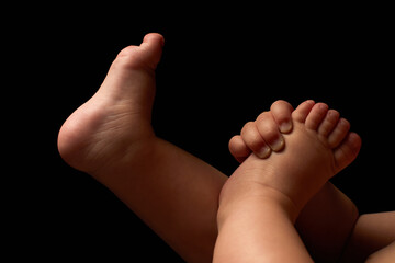 Close up newborn fingers feet and hands isolated on black background 