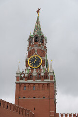 Fototapeta na wymiar View of Spasskaya Tower made from red bricks. It's a part of Moscow Kremlin on Red Square. Cloudy sky in the background. On the clock 12:40. Theme of travel in Russia.