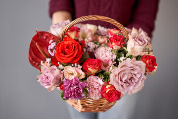 Flower arrangement in Wicker basket. Beautiful bouquet of mixed flowers in woman hand. Handsome fresh bouquet. Small flower shop and Flowers delivery.