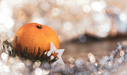 Mandarine mit weißem Stern vor weihnachtlich, leuchtenden Hintergrund mit schönem Bokeh. Weihnachtskarte