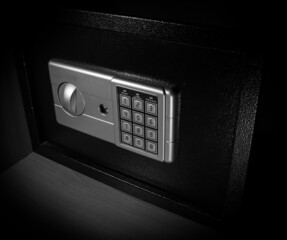 Small modern safe on shelf in dark. Small safe box close up in low key light