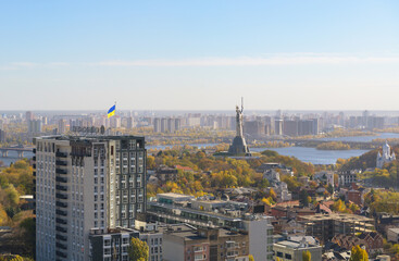 Obraz premium Beautiful panorama of autumn Kiev. View from the left bank to the Dnieper. Wide river in the city and autumn yellow trees.Village and city