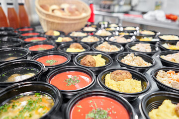 Food delivery. Different in plastic disposable lunch box with healthy natural food. Chicken broth, mashed soup, mashed potatoes with cutlet, seafood pasta, salads, pilaf with a fresh bun.