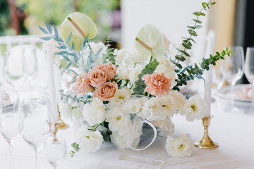 Floral decorations on summer party table. Centerpiece with rose, dahlia and hortensia flowers. White plates, table cloth, romantic wedding reception.