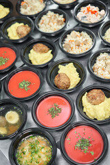Row of plastic disposable lunch box with healthy natural food. Soups, cream soup, main course with side dish, salads. Food delivery. Lunch in the office.