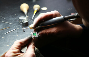 Jewelry workshop. Jeweler holding a diamond emerald ring - obrazy, fototapety, plakaty