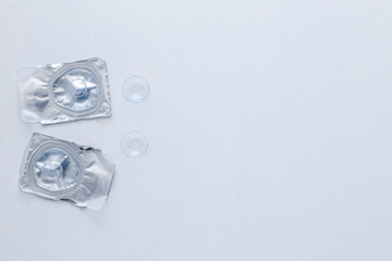 Two contact lenses in a closed package and two open contact lenses lie on the side on a white...